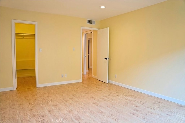 unfurnished bedroom with visible vents, baseboards, wood finished floors, and a spacious closet