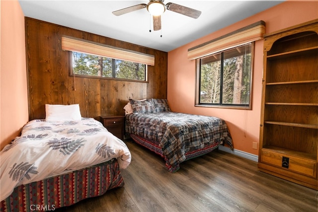 bedroom with baseboards, multiple windows, wood finished floors, and a ceiling fan