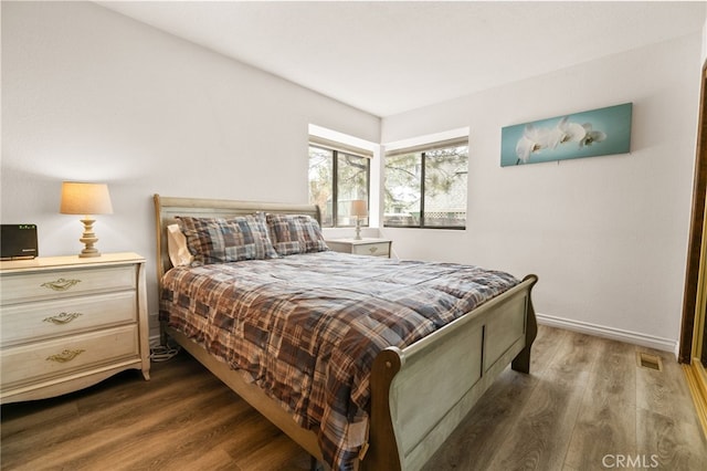 bedroom featuring visible vents, baseboards, and wood finished floors