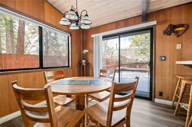 dining area with wood walls and an inviting chandelier