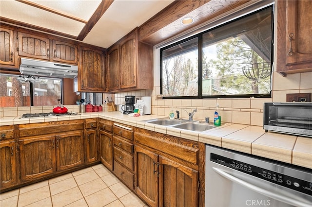 kitchen featuring under cabinet range hood, a wealth of natural light, decorative backsplash, gas stovetop, and stainless steel dishwasher