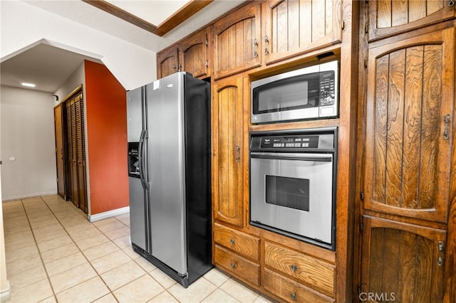 kitchen with light tile patterned floors, brown cabinets, and stainless steel appliances