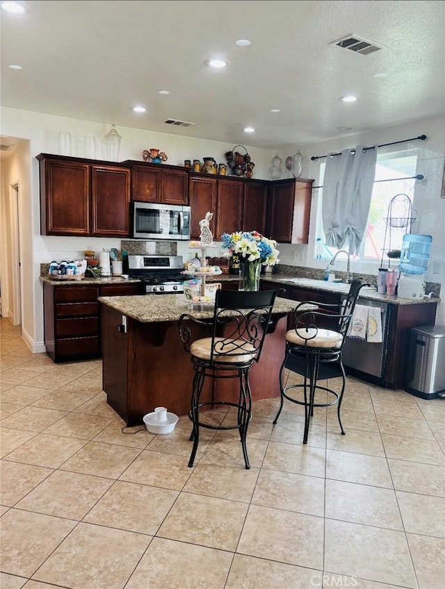 kitchen featuring light stone counters, visible vents, appliances with stainless steel finishes, and light tile patterned floors