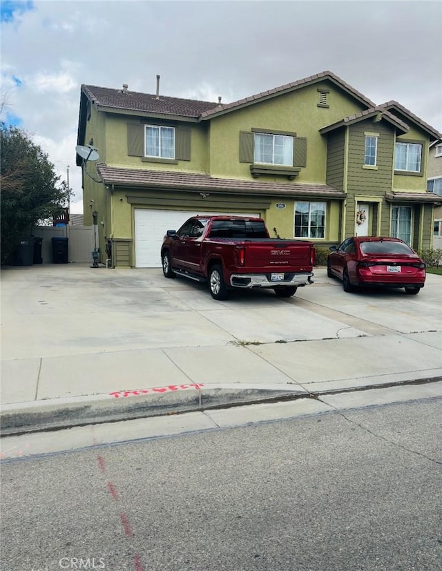 traditional-style house with stucco siding, concrete driveway, and a garage