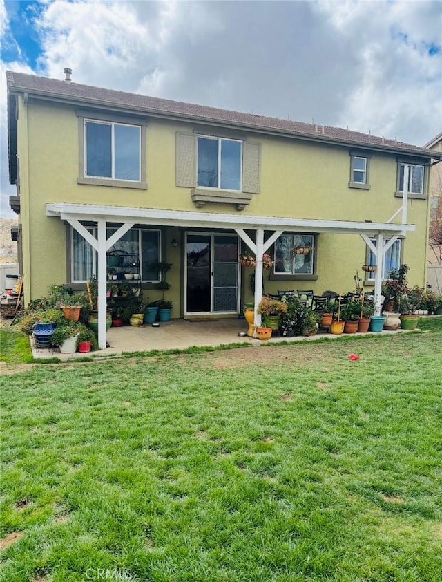 back of property with a lawn and stucco siding