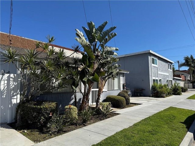 view of side of home featuring stucco siding and fence