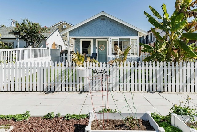 bungalow-style house with a garden, a fenced front yard, and covered porch