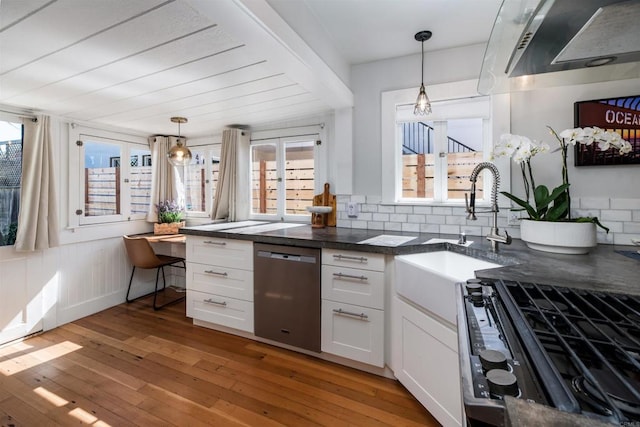 kitchen with white cabinetry, light wood-style floors, stainless steel dishwasher, dark countertops, and tasteful backsplash