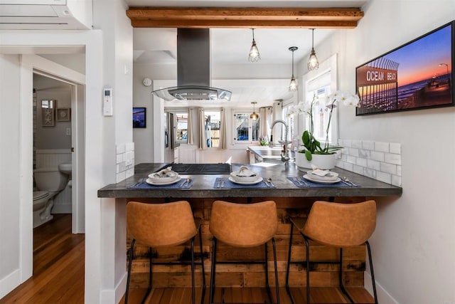 dining space featuring beamed ceiling, wood finished floors, and baseboards