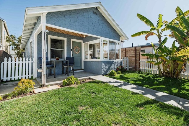 back of property with fence, a lawn, and stucco siding