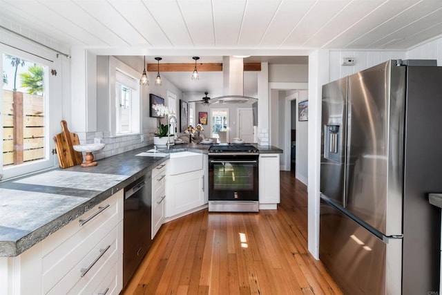 kitchen with black appliances, light wood-style flooring, dark countertops, exhaust hood, and white cabinets