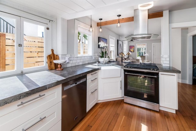 kitchen featuring island exhaust hood, dark countertops, dishwasher, and black gas stove