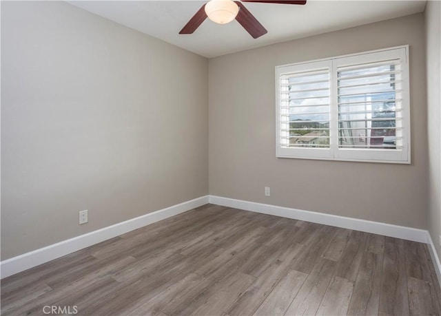 spare room featuring a ceiling fan, baseboards, and wood finished floors