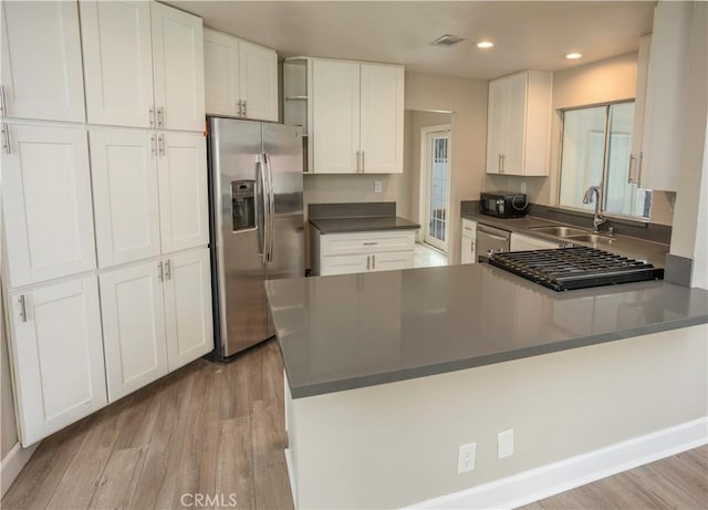 kitchen featuring a sink, stainless steel appliances, light wood-type flooring, and white cabinets