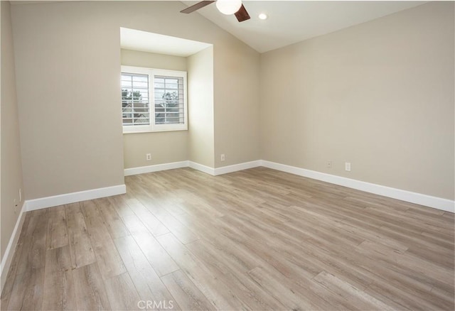 spare room with baseboards, lofted ceiling, a ceiling fan, and light wood finished floors