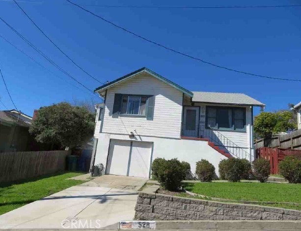 traditional-style home with an attached garage, concrete driveway, a front yard, and fence