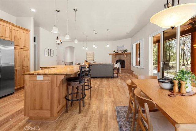 13725 Nimshew Rd, Magalia, CA 95954 - kitchen with a kitchen island, a fireplace, light brown cabinetry, light wood-style floors, and stainless steel fridge