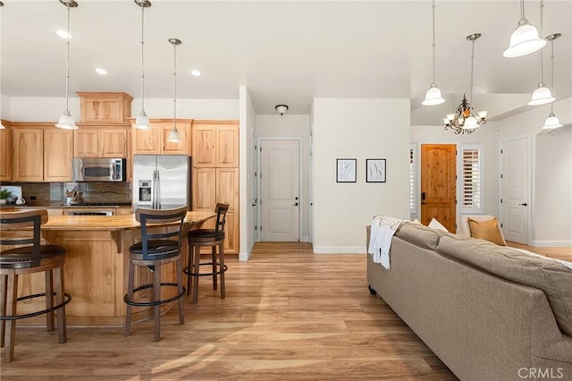13725 Nimshew Rd, Magalia, CA 95954 - kitchen with tasteful backsplash, open floor plan, a kitchen bar, light wood-type flooring, and stainless steel appliances