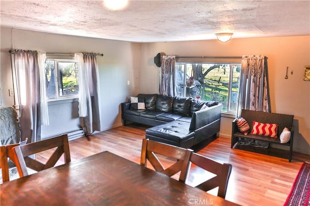 living room with baseboards, a textured ceiling, baseboard heating, and wood finished floors