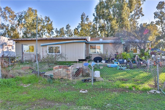 rear view of property featuring a yard and fence