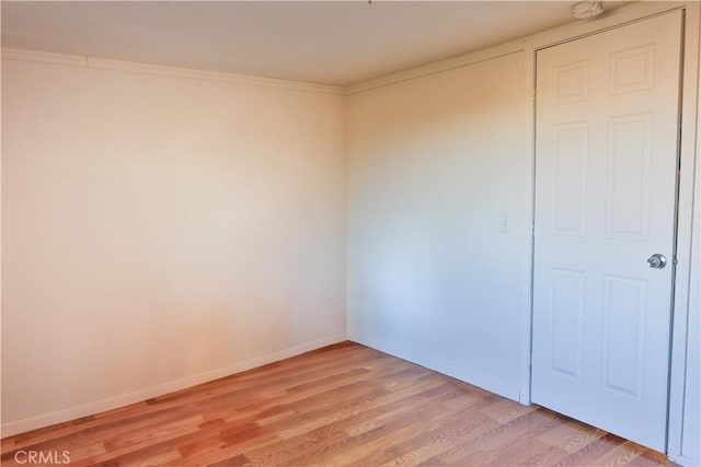 spare room with light wood-style flooring, baseboards, and ornamental molding