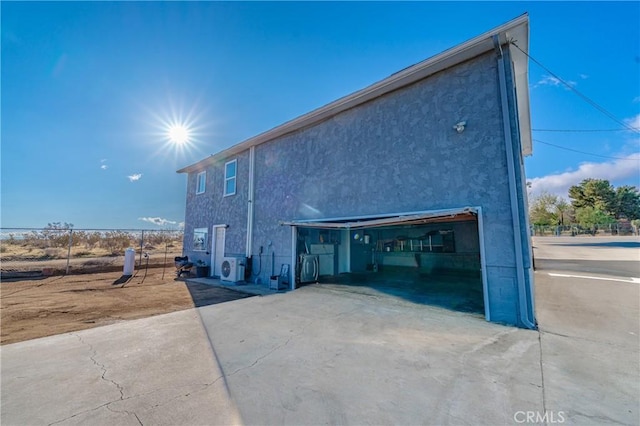 view of home's exterior with fence, driveway, stucco siding, a garage, and ac unit