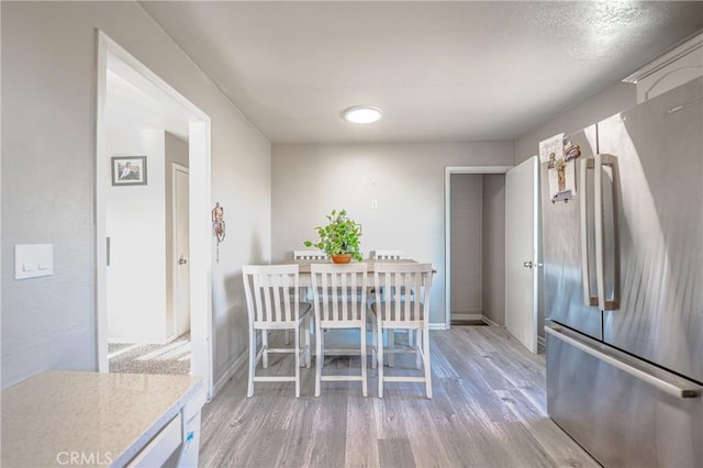 dining room featuring light wood-style flooring and baseboards