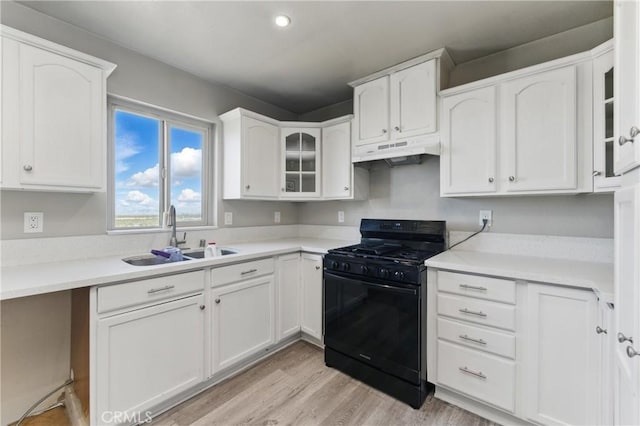 kitchen with white cabinetry, under cabinet range hood, black range with gas stovetop, and a sink