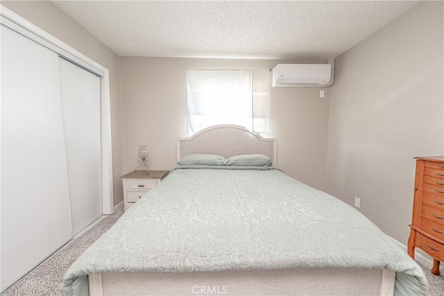 bedroom featuring light colored carpet, a textured ceiling, a closet, and a wall mounted AC