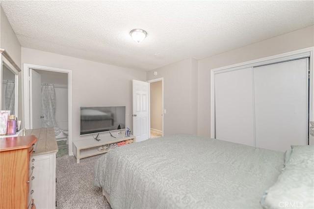 bedroom with a closet, connected bathroom, a textured ceiling, and carpet floors