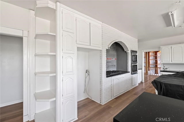 kitchen with open shelves, dark wood-style floors, white cabinetry, stainless steel double oven, and gas stovetop