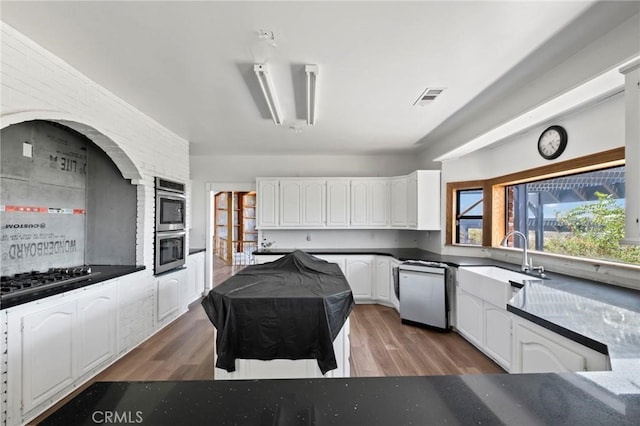 kitchen featuring visible vents, white cabinetry, gas stovetop, light wood finished floors, and dishwashing machine