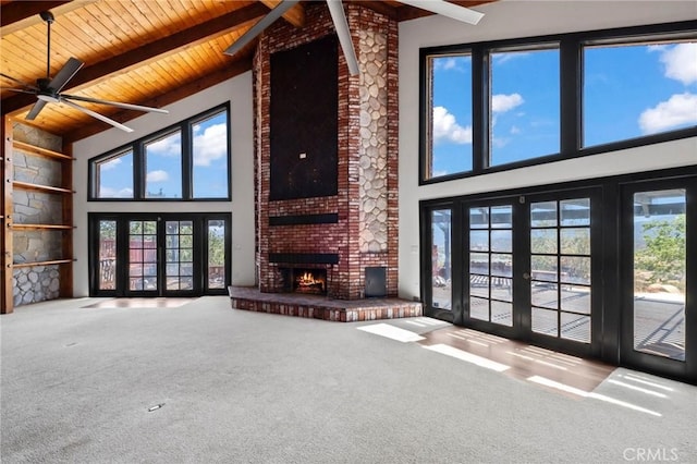 unfurnished living room with a fireplace, french doors, wooden ceiling, beamed ceiling, and carpet flooring