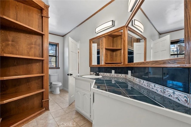 bathroom with double vanity, ornamental molding, tile patterned flooring, a sink, and toilet