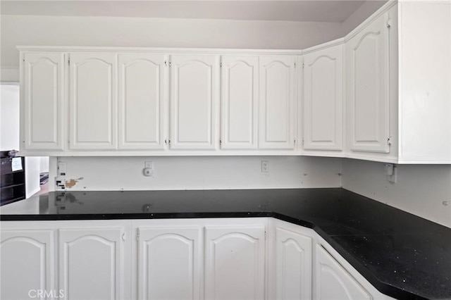 kitchen featuring dark countertops and white cabinetry