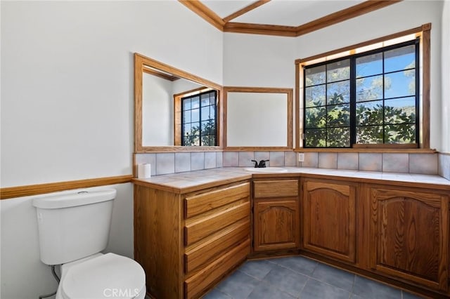 bathroom with tile patterned floors, toilet, vanity, and ornamental molding