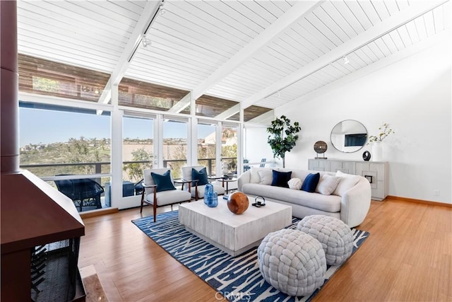 living room with light wood finished floors, track lighting, baseboards, floor to ceiling windows, and lofted ceiling with beams