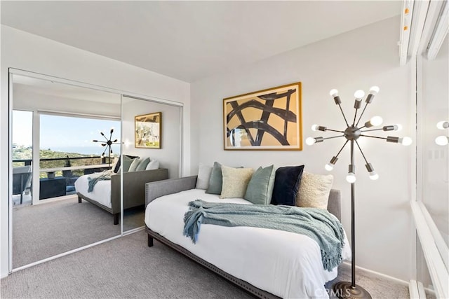 carpeted bedroom featuring a closet and an inviting chandelier