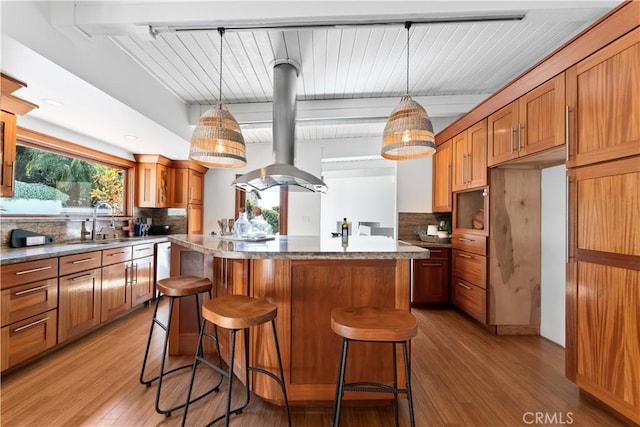 kitchen featuring light wood-style flooring, a center island, beamed ceiling, backsplash, and island range hood