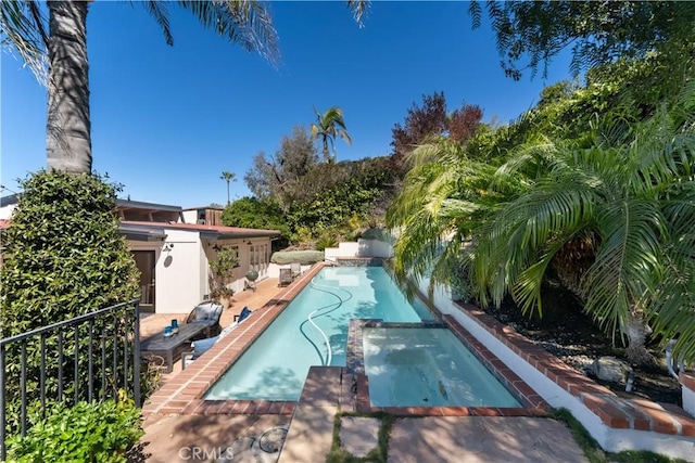 view of swimming pool with a pool with connected hot tub and fence