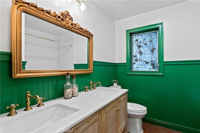 full bathroom with wainscoting, toilet, and a sink