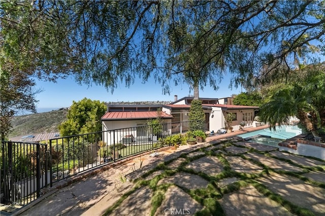 rear view of property featuring a standing seam roof, a patio, fence, metal roof, and a fenced in pool