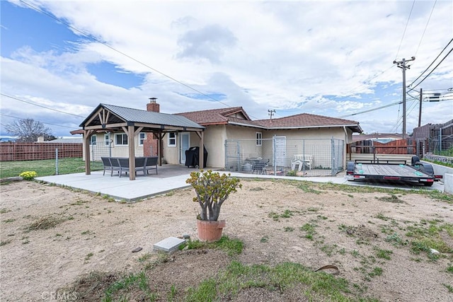 rear view of house with a patio, stucco siding, a fenced backyard, and a chimney