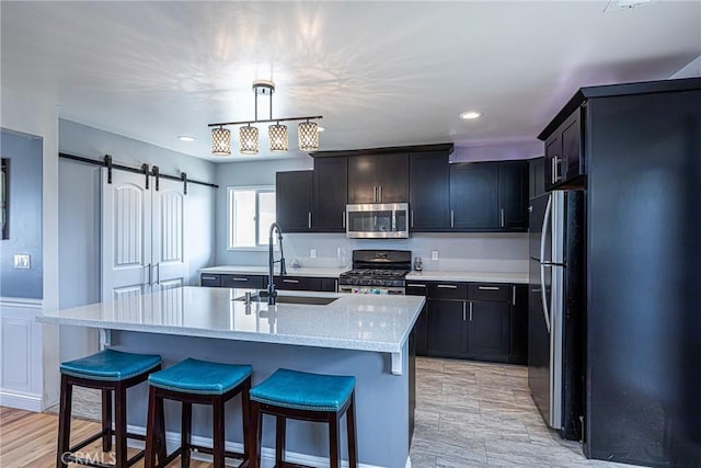 kitchen featuring a sink, a barn door, a kitchen breakfast bar, and stainless steel appliances