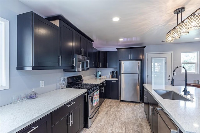 kitchen with light stone countertops, decorative light fixtures, recessed lighting, appliances with stainless steel finishes, and a sink