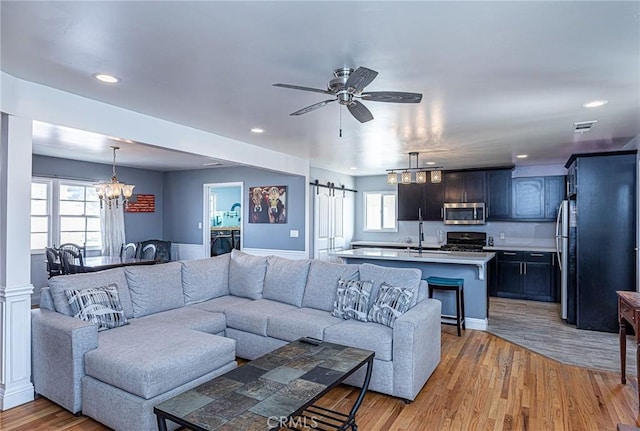 living room featuring light wood finished floors, recessed lighting, ceiling fan with notable chandelier, and visible vents