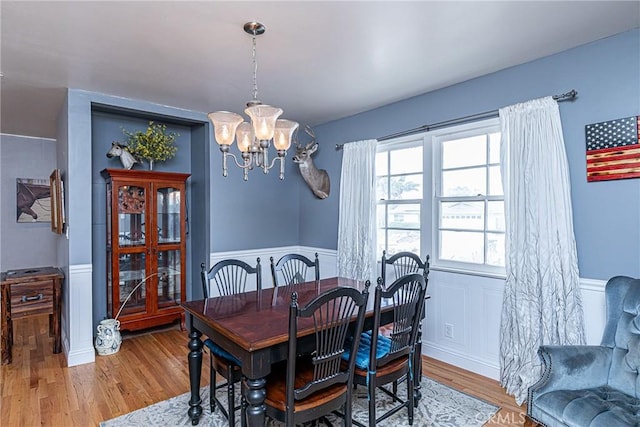 dining room featuring a notable chandelier, wood finished floors, and wainscoting