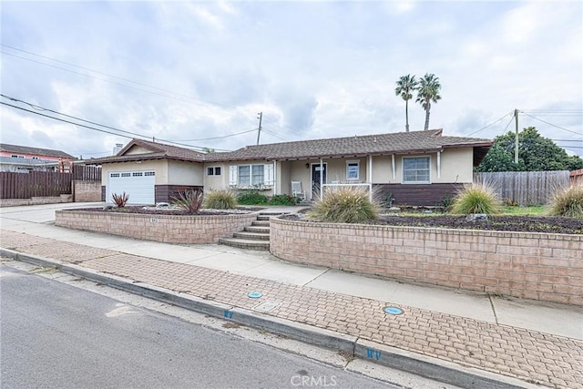 single story home featuring stucco siding, concrete driveway, a garage, and fence