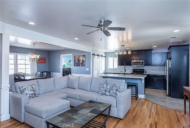 living area with ceiling fan with notable chandelier, recessed lighting, light wood-style floors, and visible vents