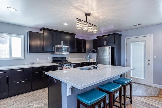 kitchen with visible vents, decorative light fixtures, a breakfast bar area, appliances with stainless steel finishes, and a sink